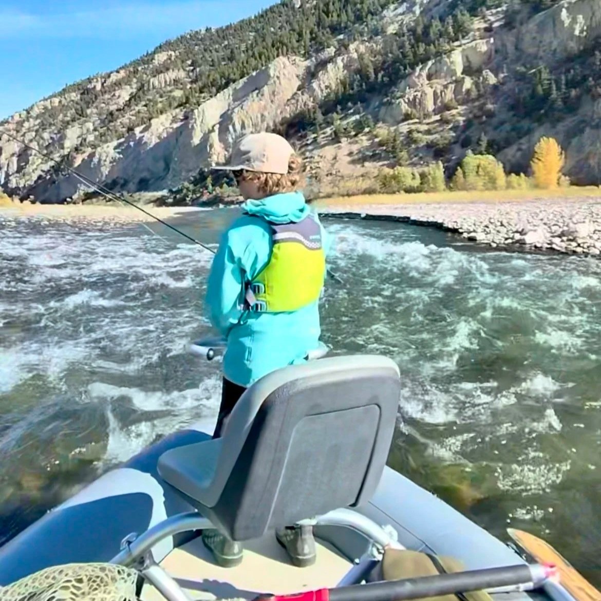 A young angler in a raft prepares to fish a deep seam below a rapid on the Yellowstone River, with an EGO net ready.
