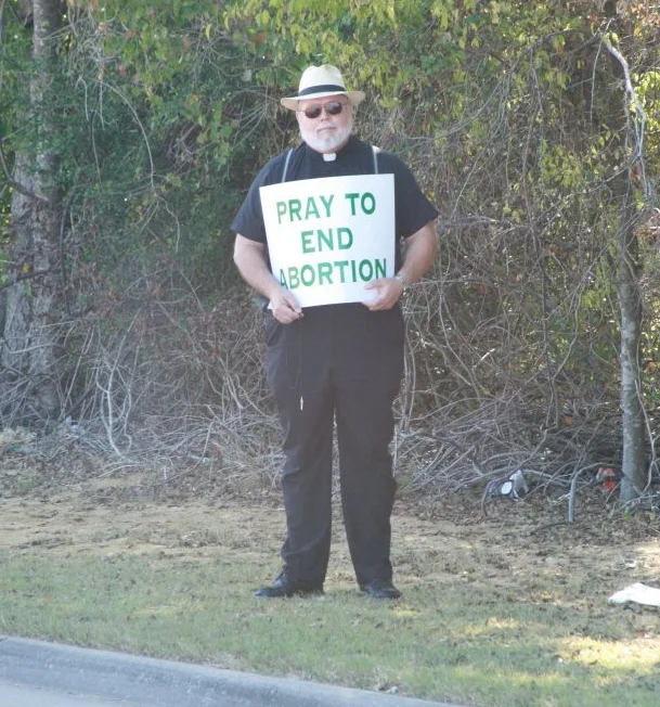 Priest Standing for Life with a Sign