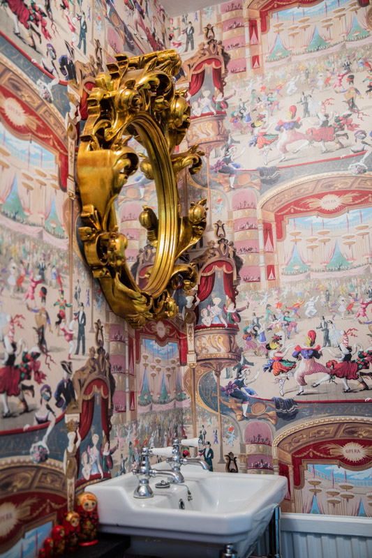Whimsical cabaret wallpaper Cole and Son in a small powder room