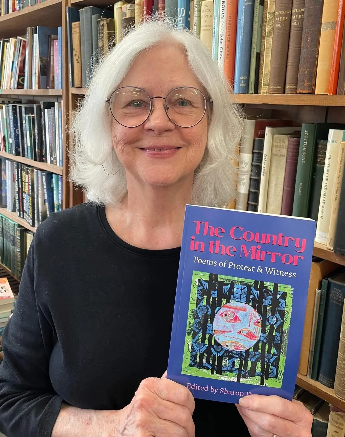 A proud editor holds a new copy of THE COUNTRY IN THE MIRROR: Poems of Protest &amp; Witness at @greenmountainbooks in Lyndonville, VT! Thank you indie bookstores for stocking this title, which has been a labor of love with editor @sharon.darrow and 