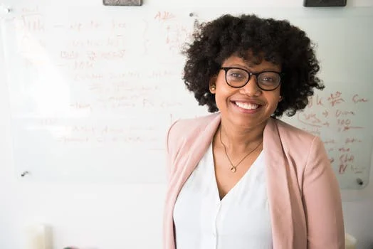 Woman pink blazer smiling glasses.jpeg