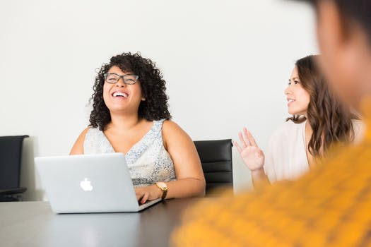 Woman laughing at conference table other women.jpeg