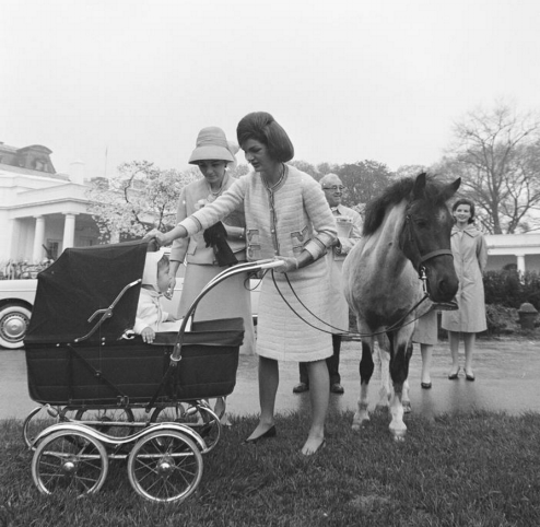Jackie Kennedy, a lifelong horsewoman, on White House lawn with Macaroni, John, Jr, and Empress Farah Pahlavi, 1962 I mage from the JFK Presidential Library