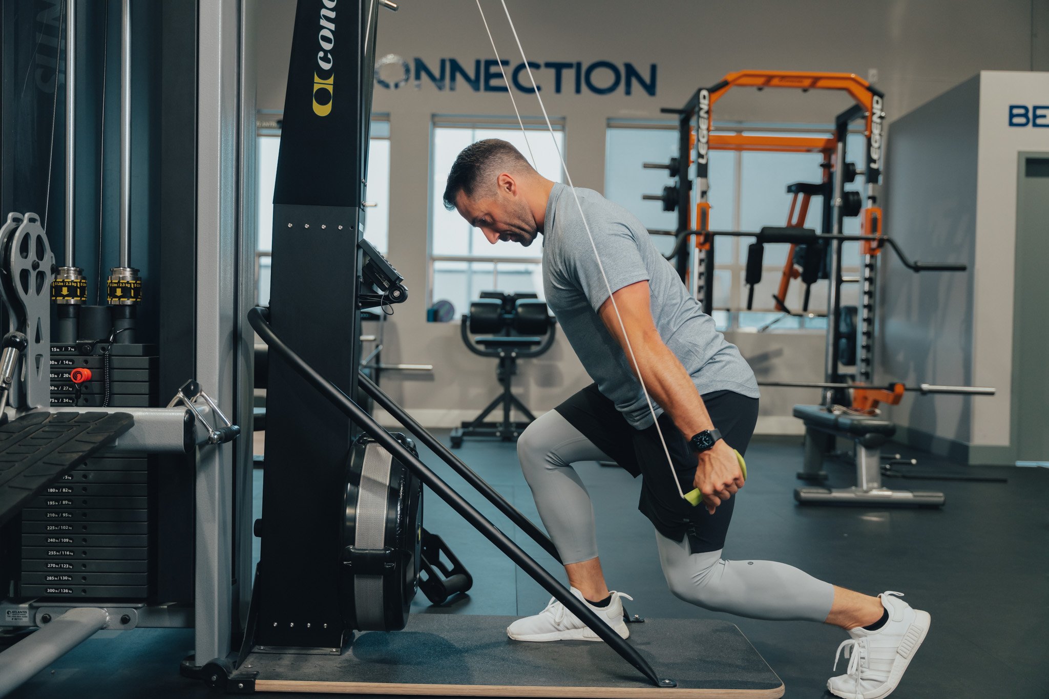 Man performing a cable tricep pushdown exercise at the gym, wearing athletic clothes.