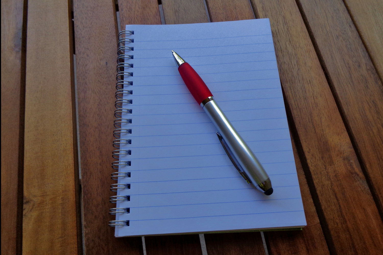 Blank spiral notepad and red pen on a wooden table, ready for sales call notes  Alt text field has the filename again — swap in the sentence above.