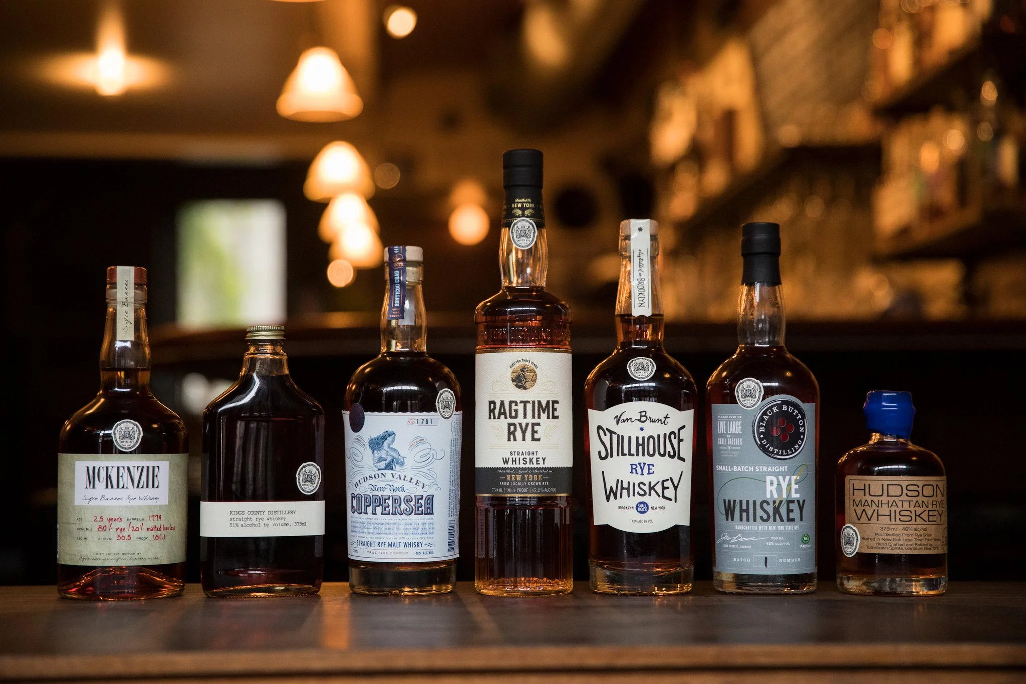 Bottles of whiskey bearing the round white Empire Rye logo, at Cardiff Giant, a bar in Brooklyn. Credit Benjamin Norman for The New York Times