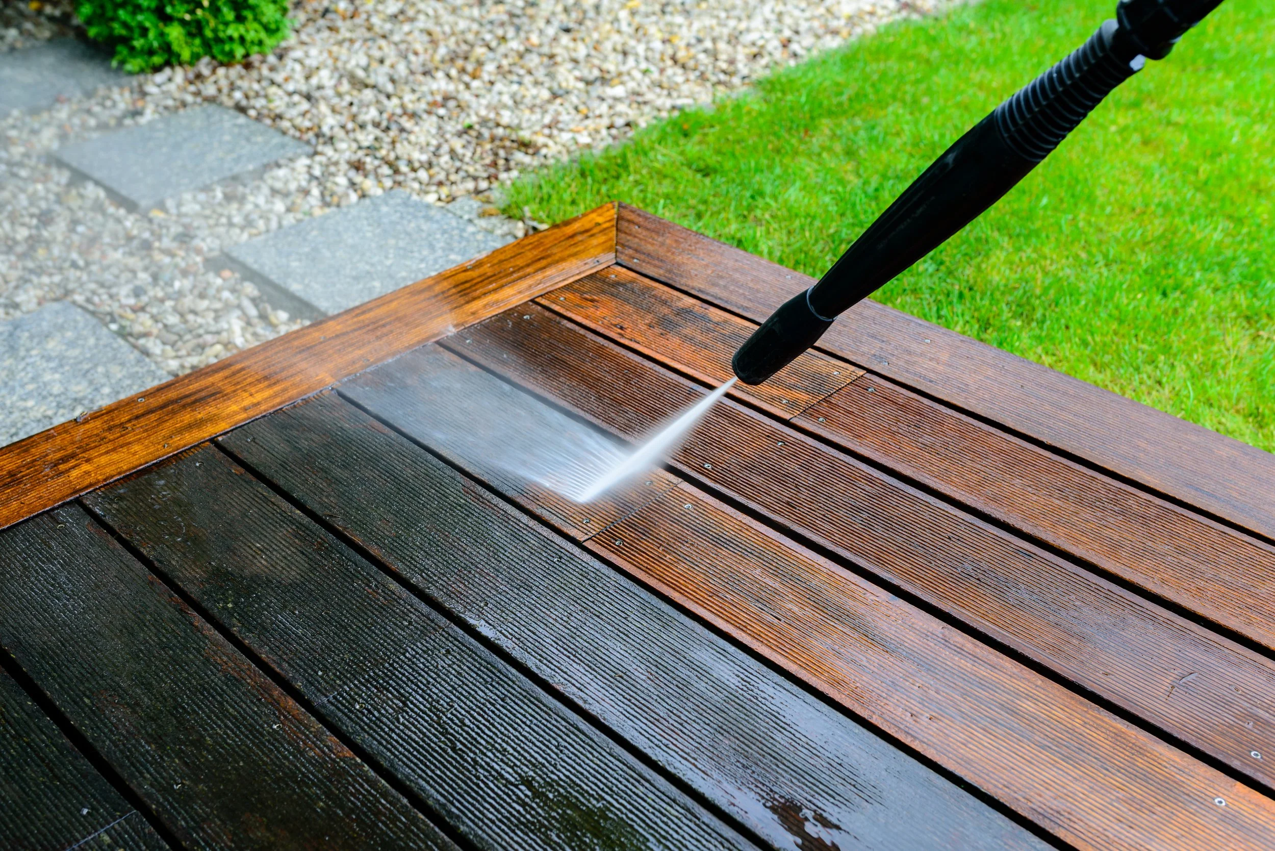 Pressure washer cleaning a wooden deck with a high-pressure water spray