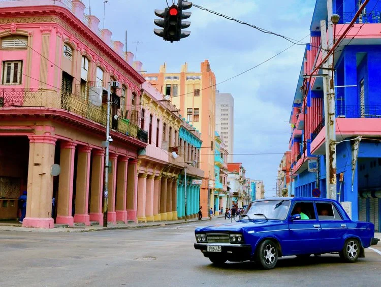 Photograph of Cuban city street with blue car and buildings by Fern Chavez