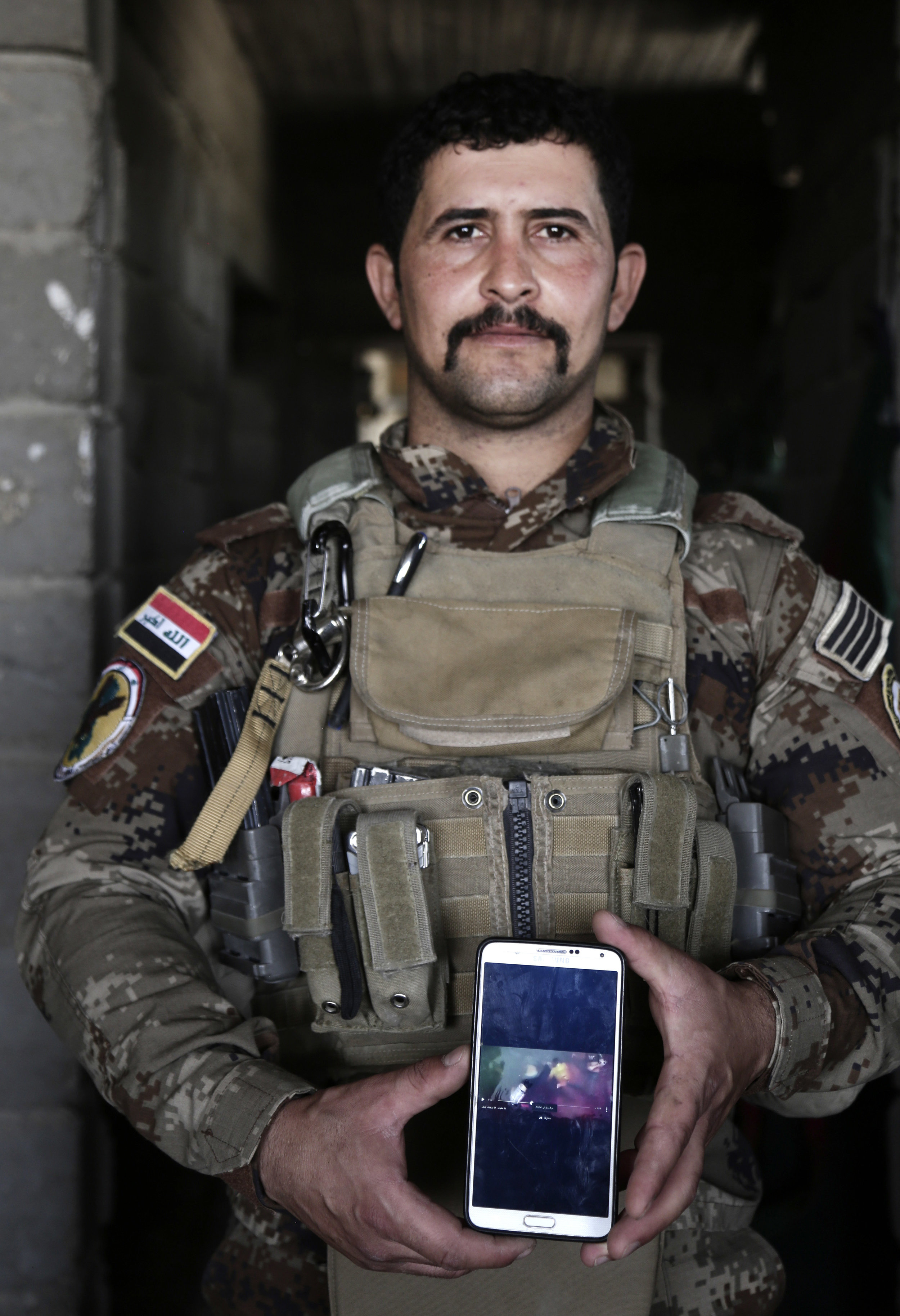 Sgt. Ahmed Abdelaziz shows an IS video of his brother's death in a mass killing of cadets. Abdelaziz has been almost continually deployed fighting the Islamic State group ever since the militants overran nearly a third of Iraq in the summer of 2014.