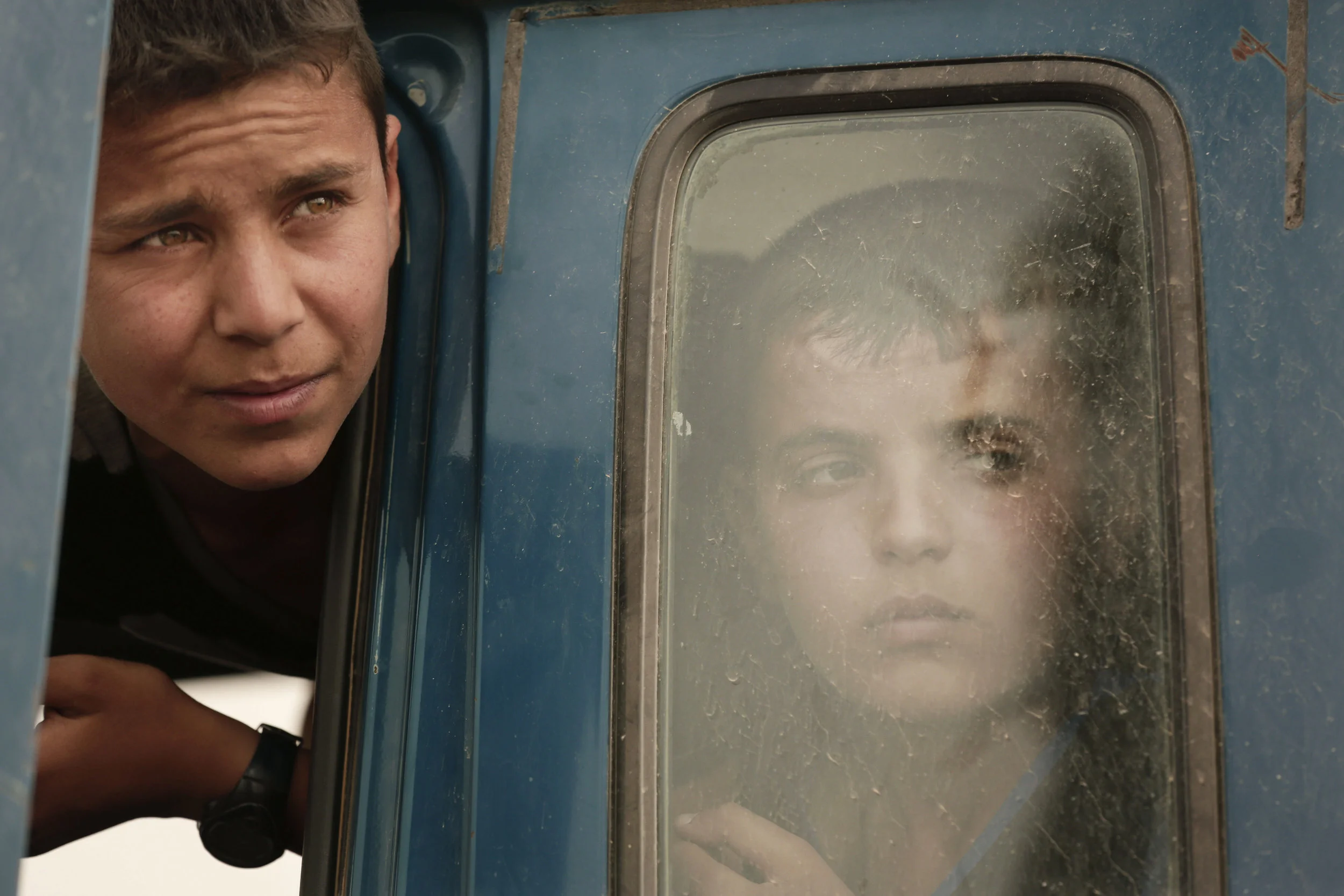 Boys fleeing Islamic State-held Hit, Iraq, wait at a checkpoint near Ramadi on March 20, 2016. 
