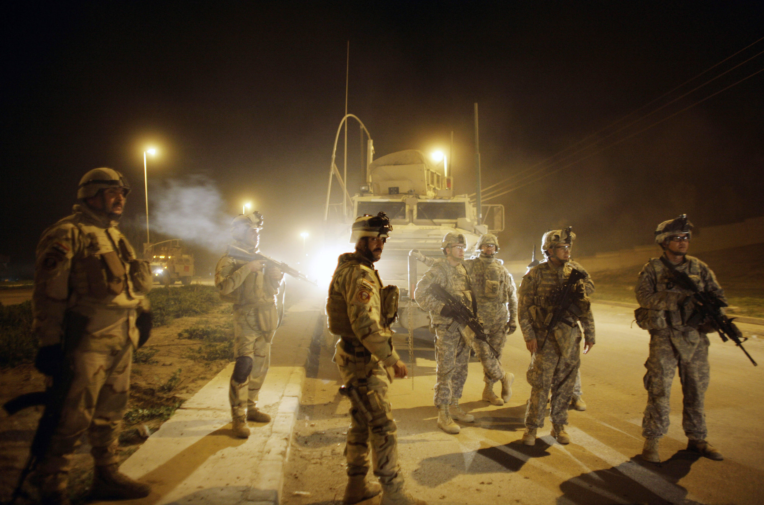 U.S. and Iraqi soldiers watch comrades detain men suspected of planting a roadside bomb after polls closed for the national election in Mosul on March 7, 2010.