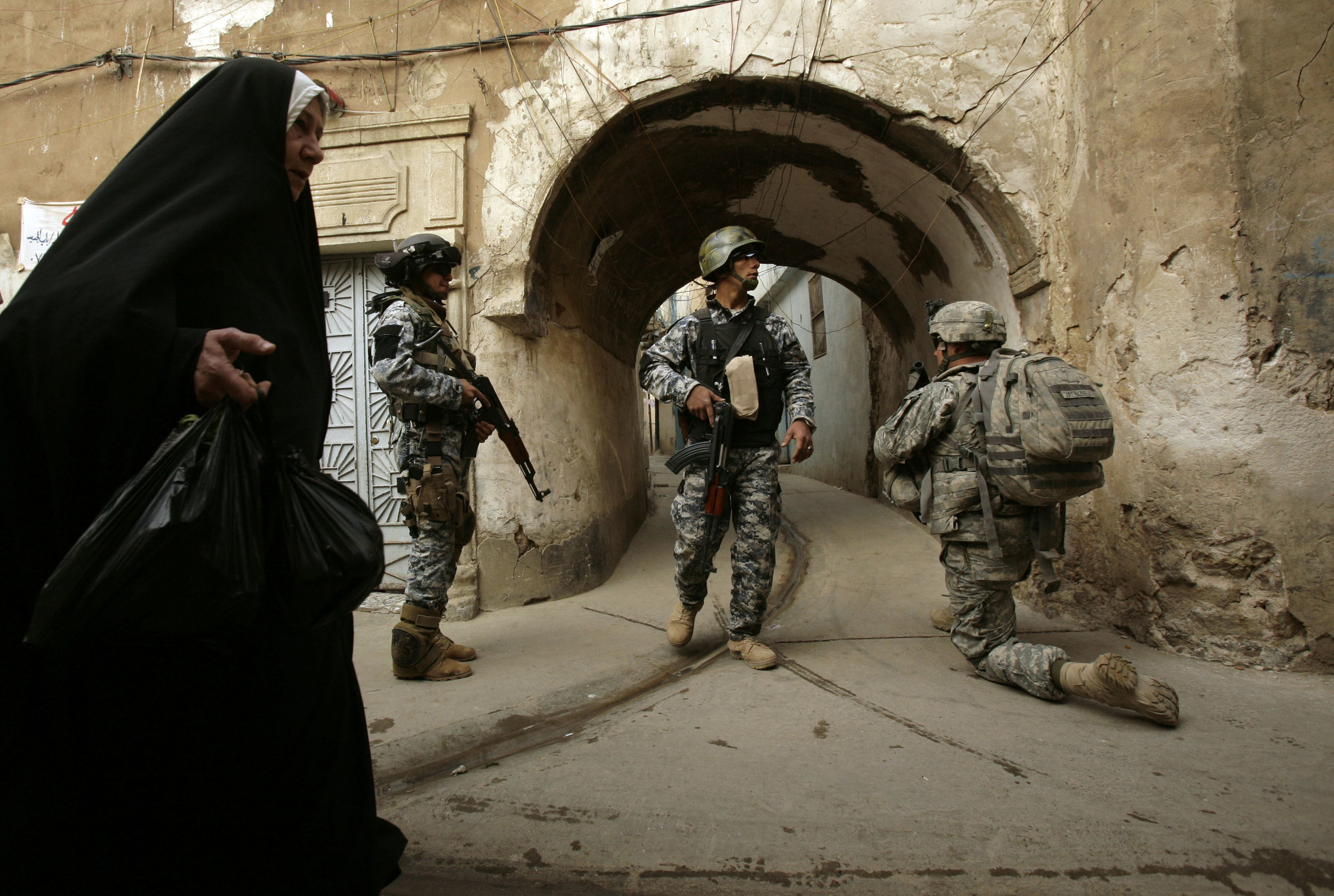 An Iraqi woman passes U.S. and Iraqi forces in the Bab al-Jadeed area of Mosul during a joint operation on west side of the city, then considered to be the last urban stronghold for al-Qaida in the country, on April 23, 2009.