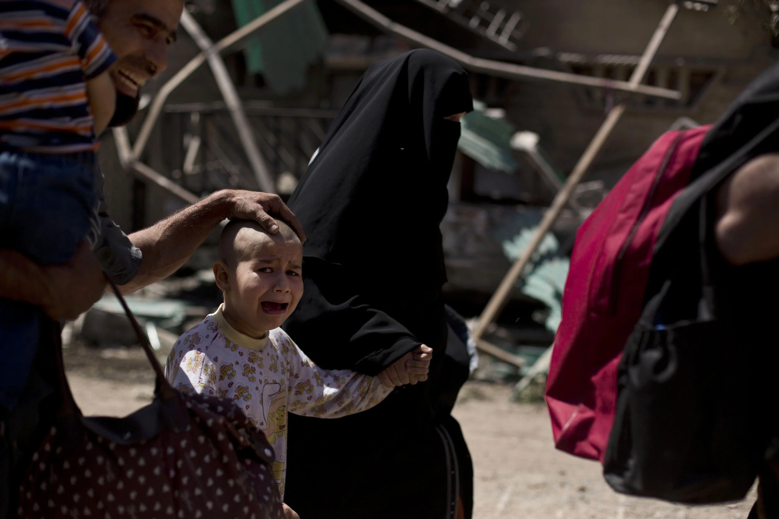 A girl with a shaved head cries as the family flees the al-Rifai neighborhood while Iraqi special forces battle Islamic State militants in Mosul on May 17, 2017.