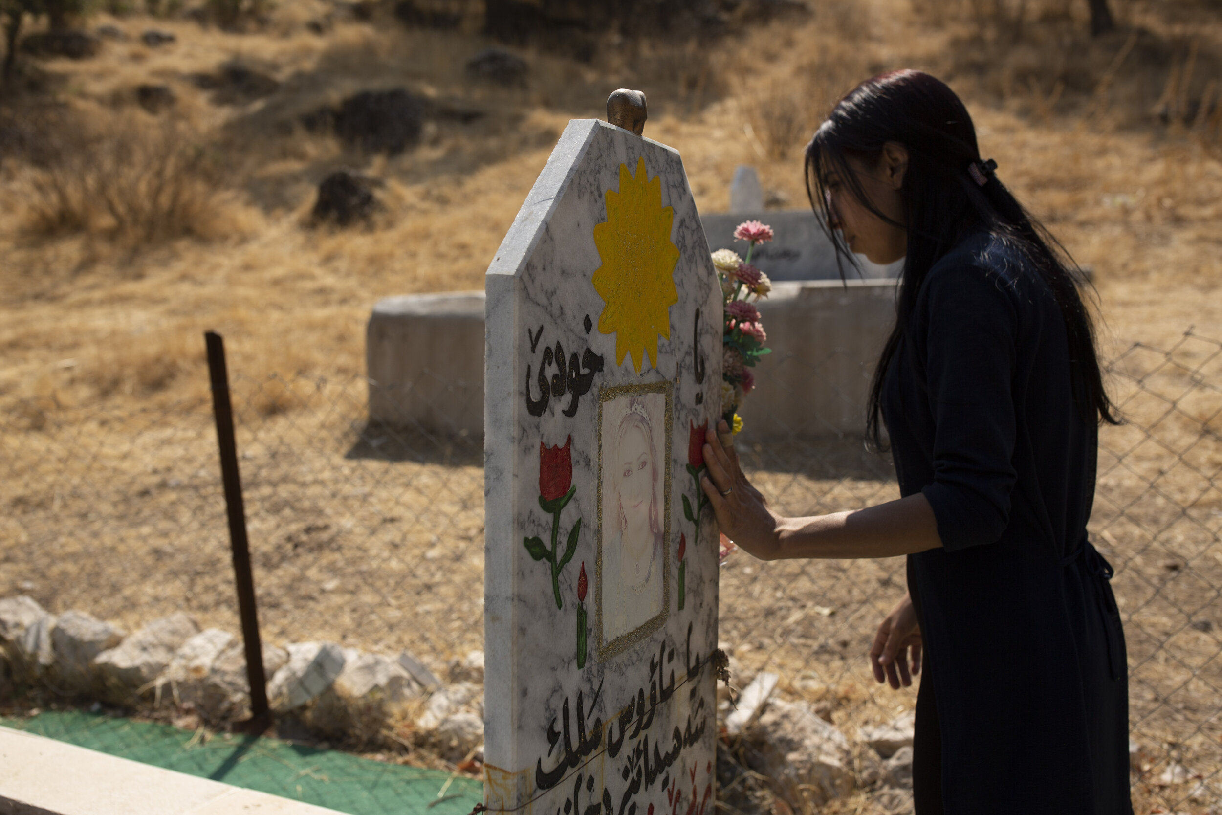 Layla Taloo visits the grave of a Yazidi woman who took her own life after she was captured by Islamic State militants in Mosul, buried on a hill overlooking the Lalish shrine in northern Iraq. (AP Photo/Maya Alleruzzo)
