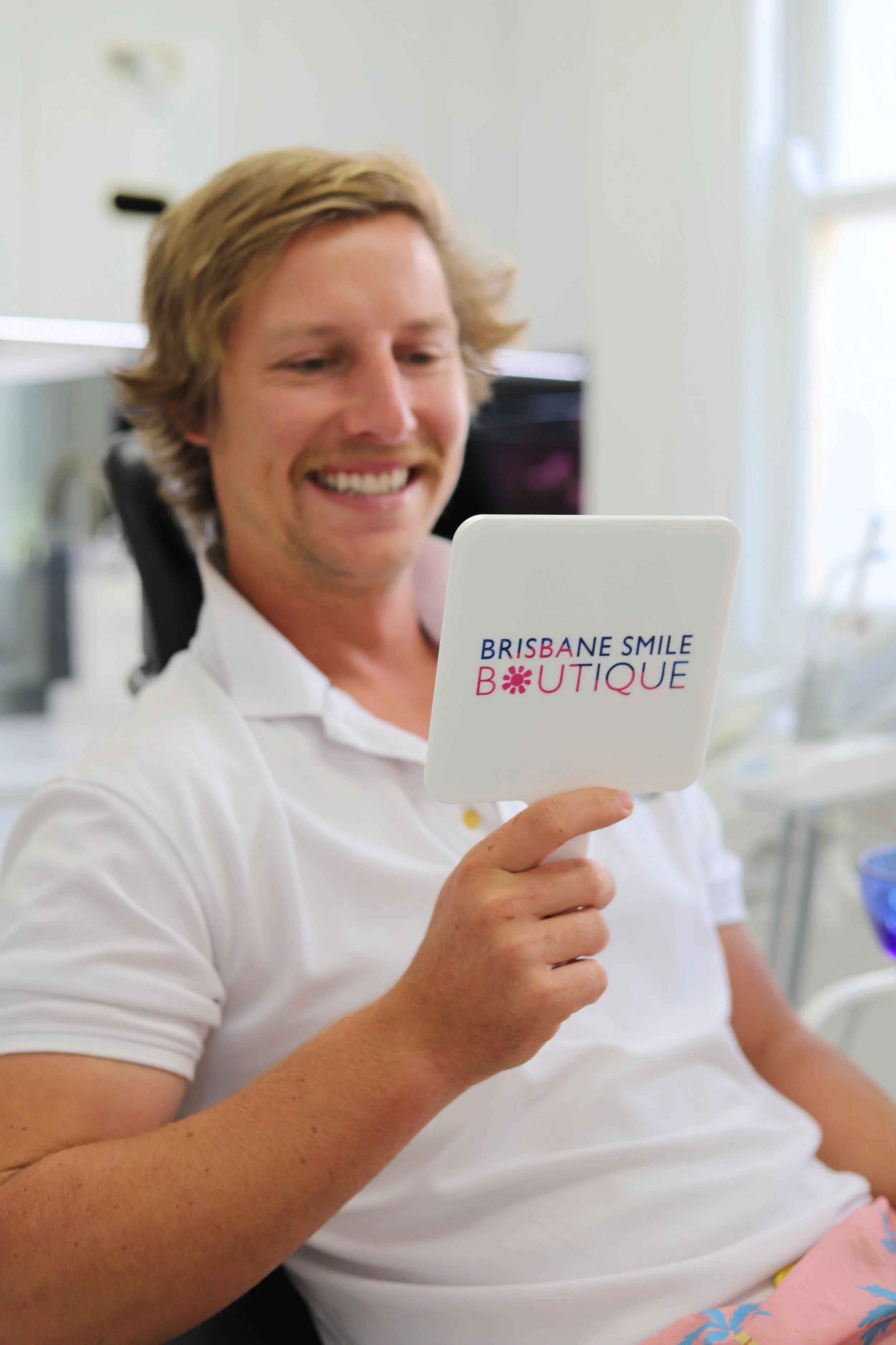 young man looking in the mirror at brisbane smile boutique after Gum Contouring in Brisbane – Subtle, Powerful Results