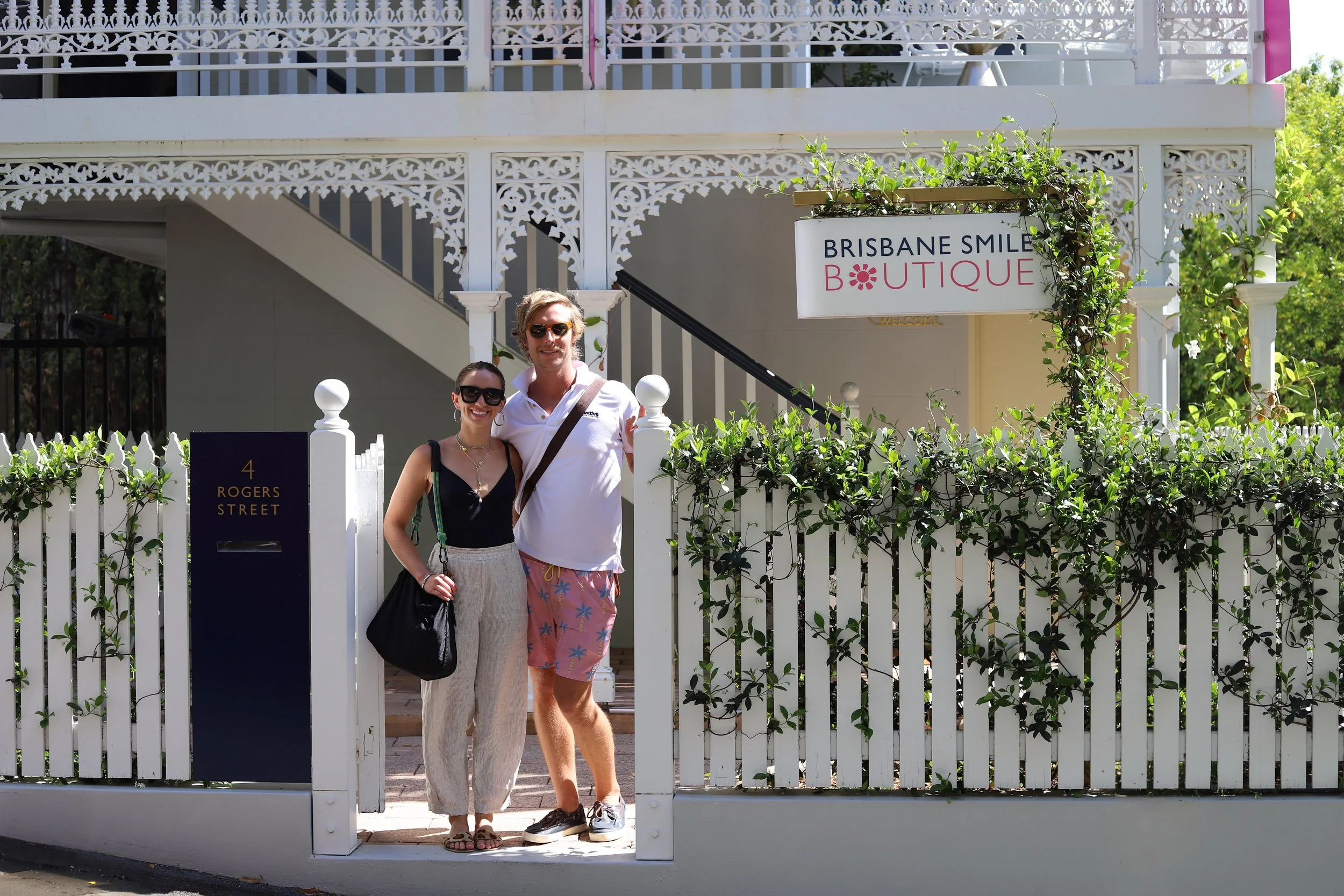 couple at a white picket fence gate in Brisbane at a dentist named Brisbane Smile Boutique