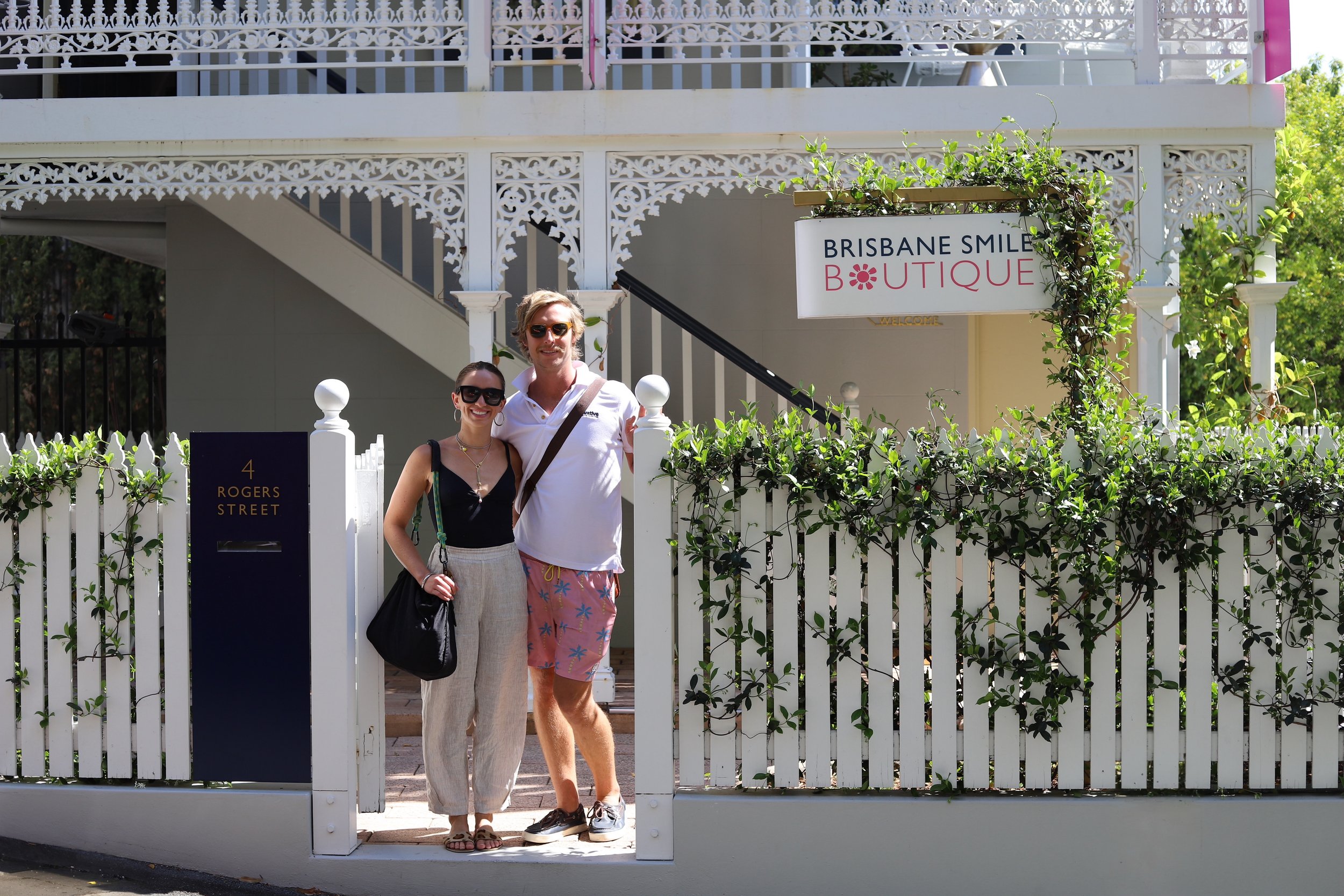 a couple standing at the front fence of a white heritage house in Brisbane, Spring Hill converted to a dental surgery