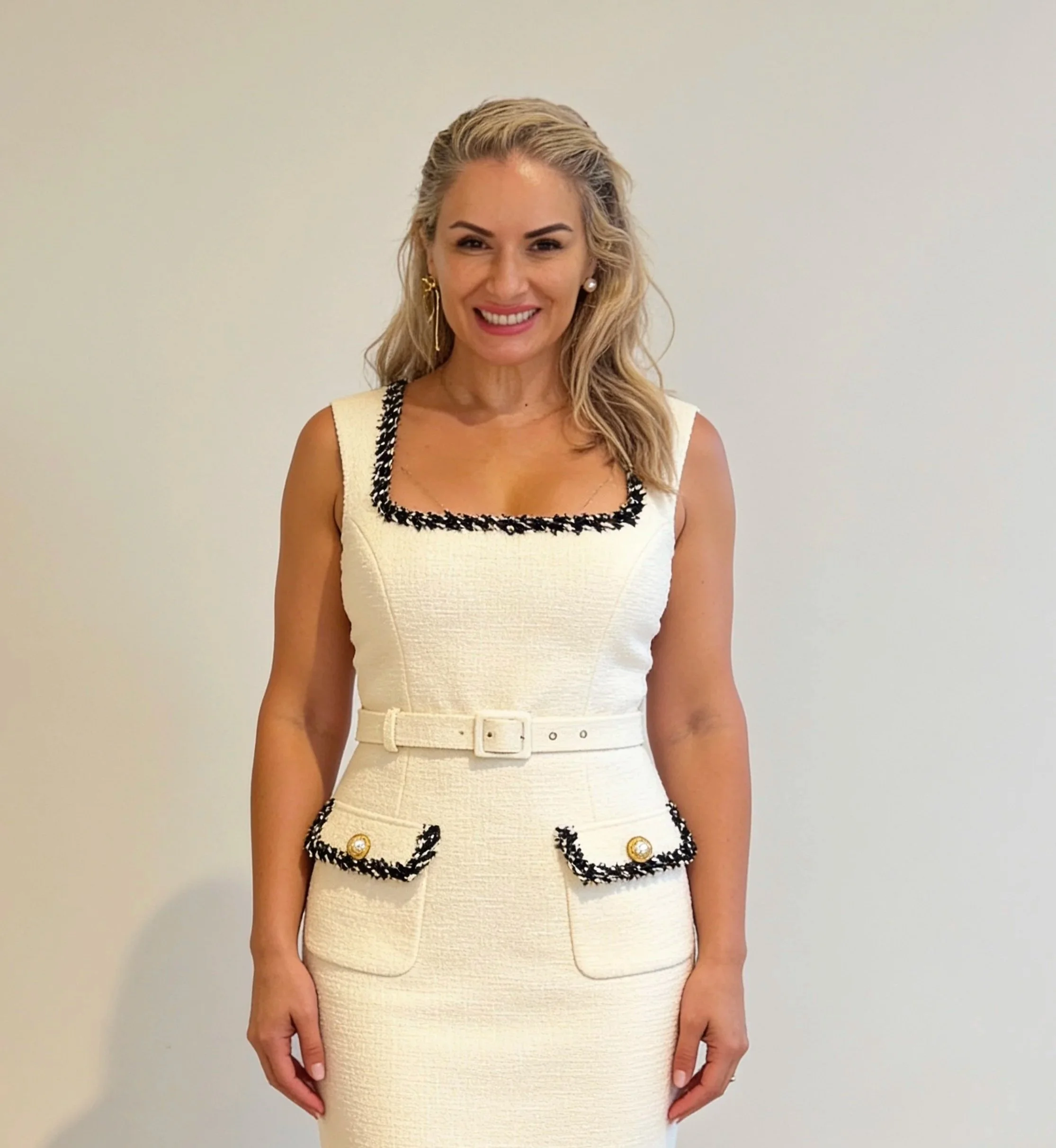 A photo of Dr Leila Haywood, an experienced female cosmetic dentist in Brisbane with blond hair and a french style cream dress on