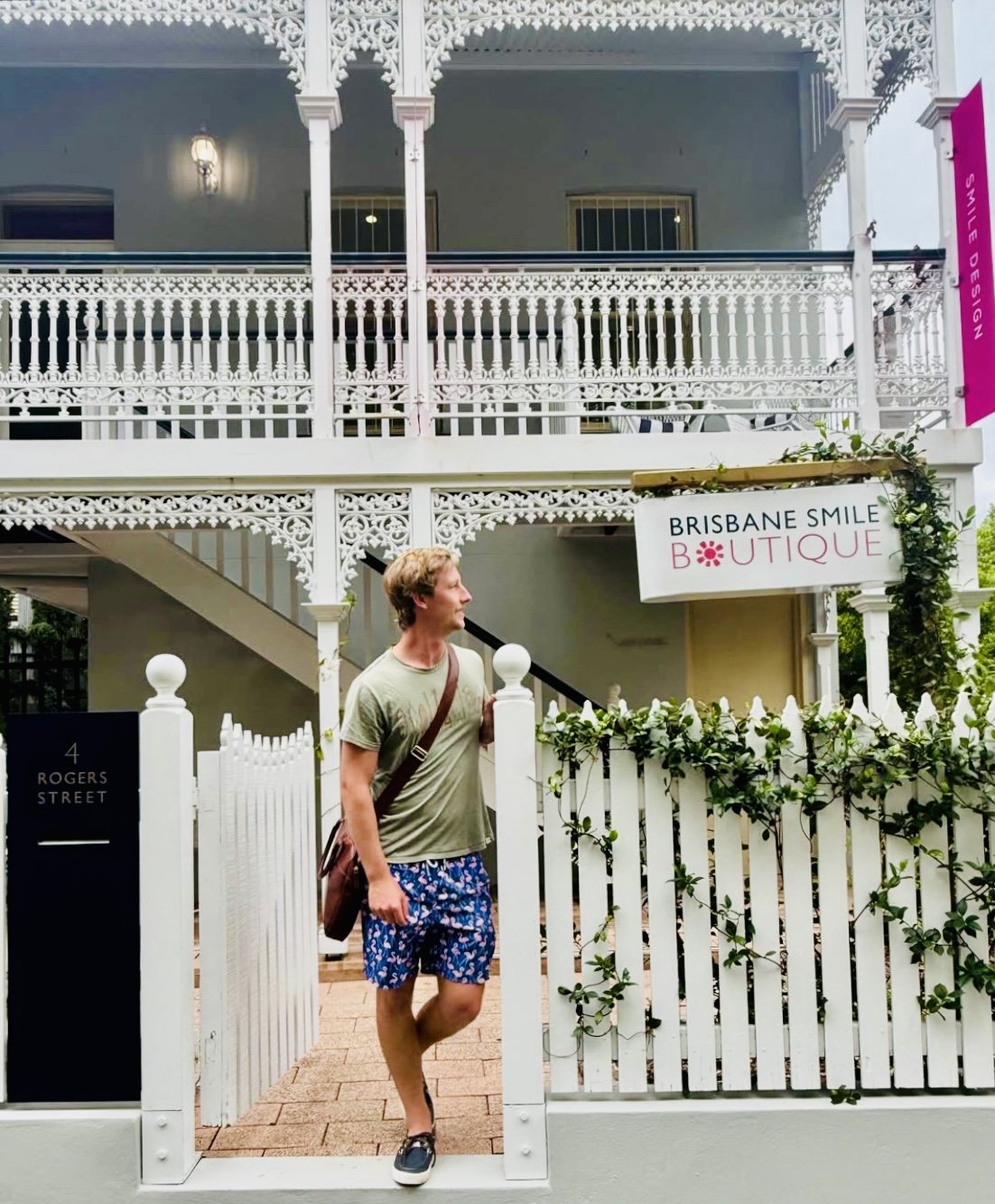 man in blueshorts at front fence of Brisbane Smile Boutique