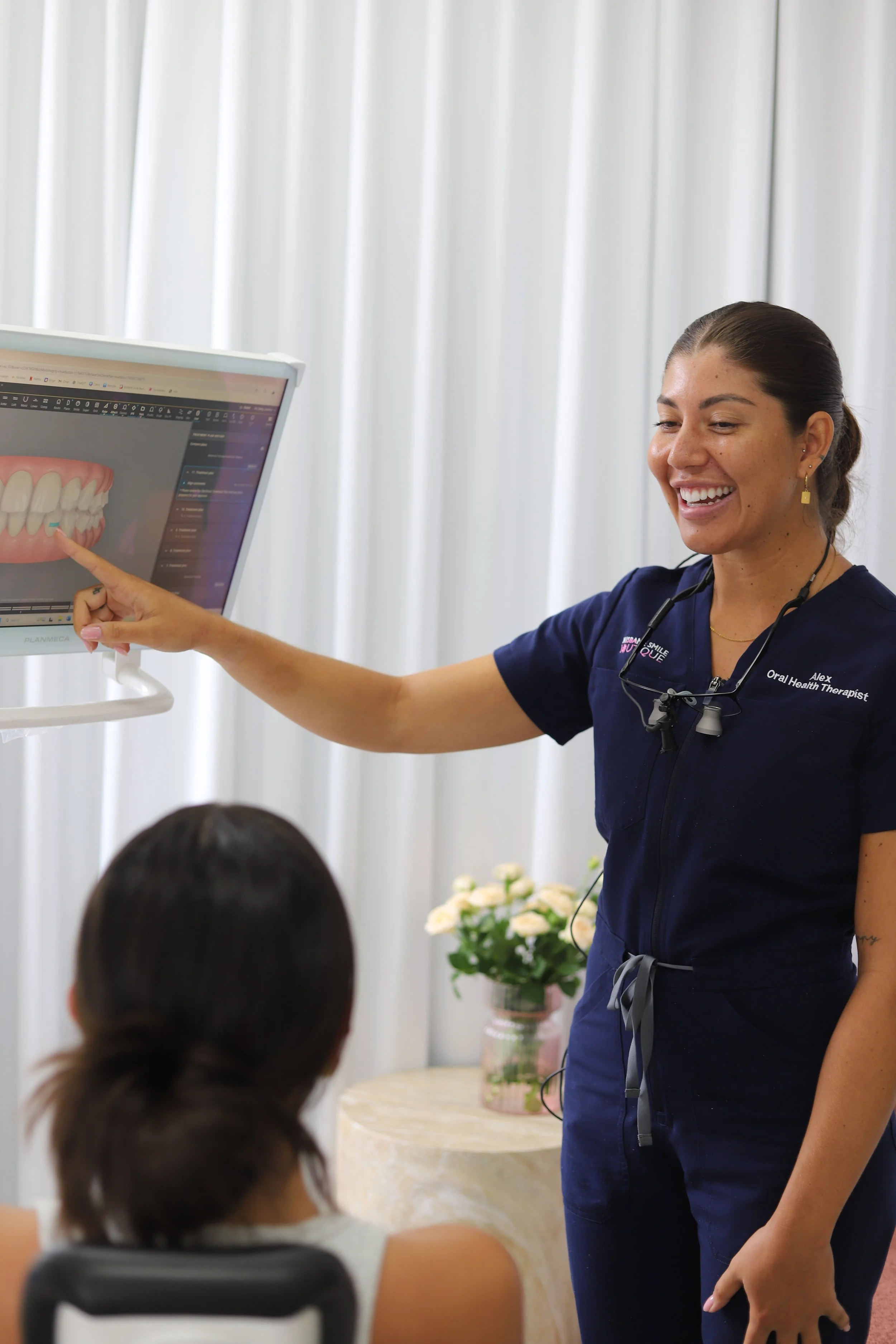 female dental professional, oral health therapist, Alexandra Forbes smiling at invisalign portal with female patient in chair at Brisbane Smile Boutique Aesthetic Dental Clinic in Spring Hill, Brisbane, Queensland, Australia