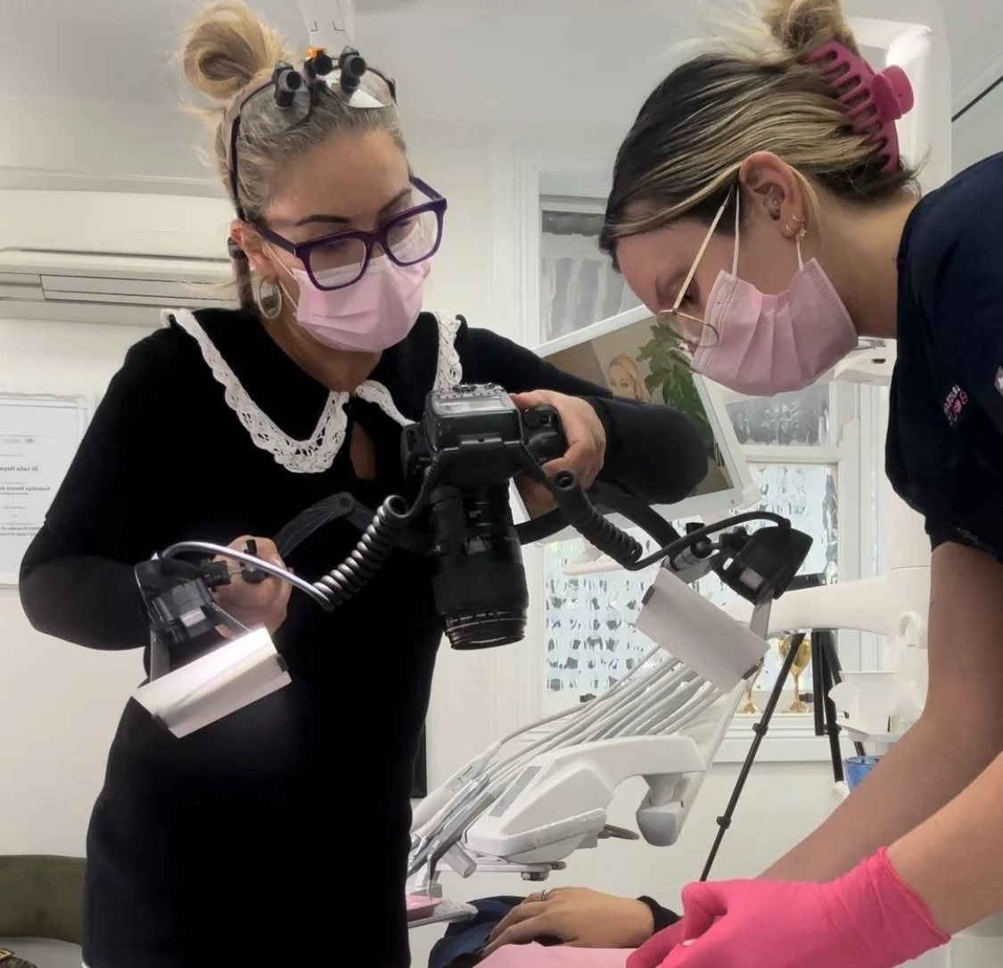 female dentist in a sandro french dress with loupes on, taking an image of a patient with a professional canon camera, with a dental assistant helping, at brisbane smile boutique, an all female aesthetic dental clinic in Spring Hill. 