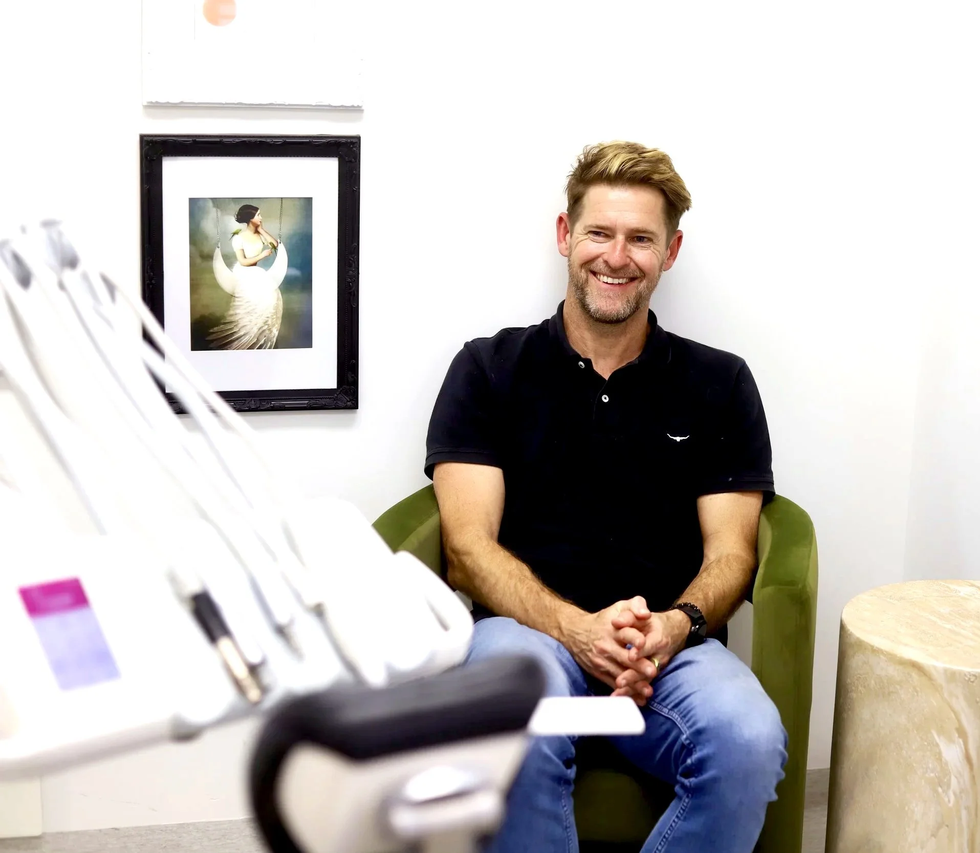 A male patient with a beard and blonde hair at the dentist in an armchair smiling at the camera, speaking to the cosmetic dentist, Dr Leila Haywood, after cosmetic edge composite resin