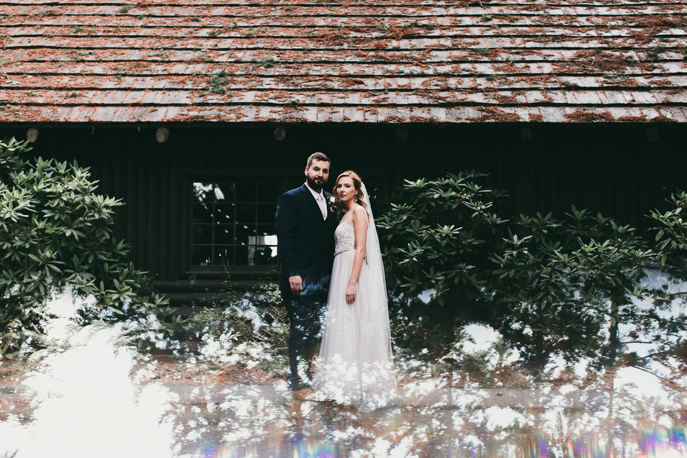 bride and groom in front of log hall at kitsap memorial state park