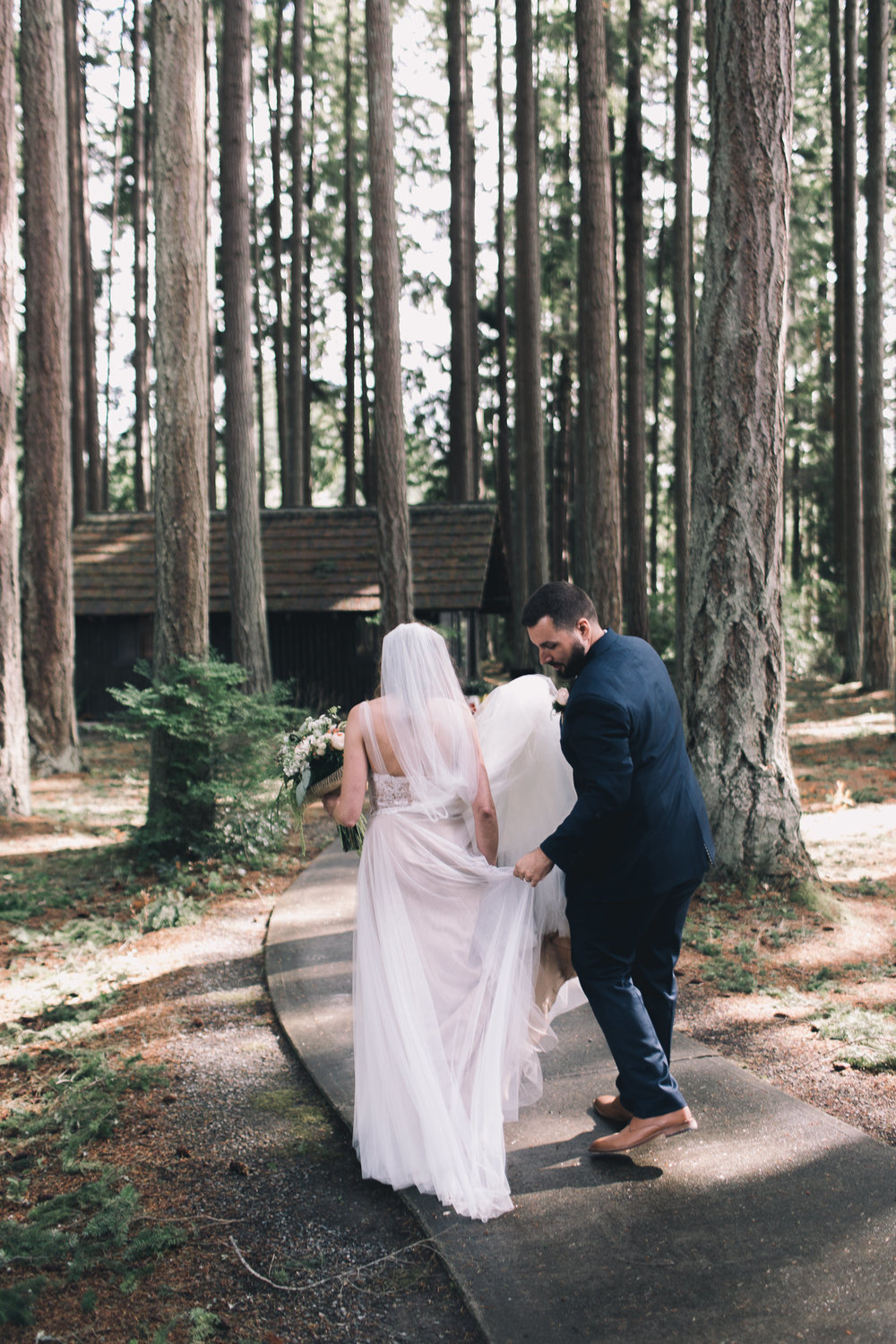 tall trees at kitsap memorial state park with bride and groom walking