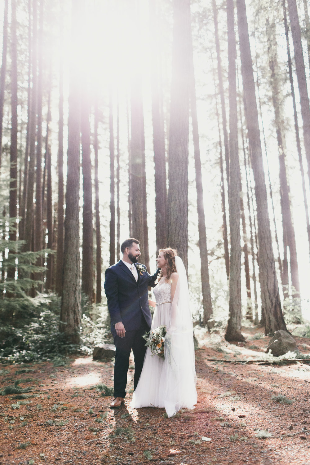 sun shining through trees at kitsap memorial state park with bride and groom