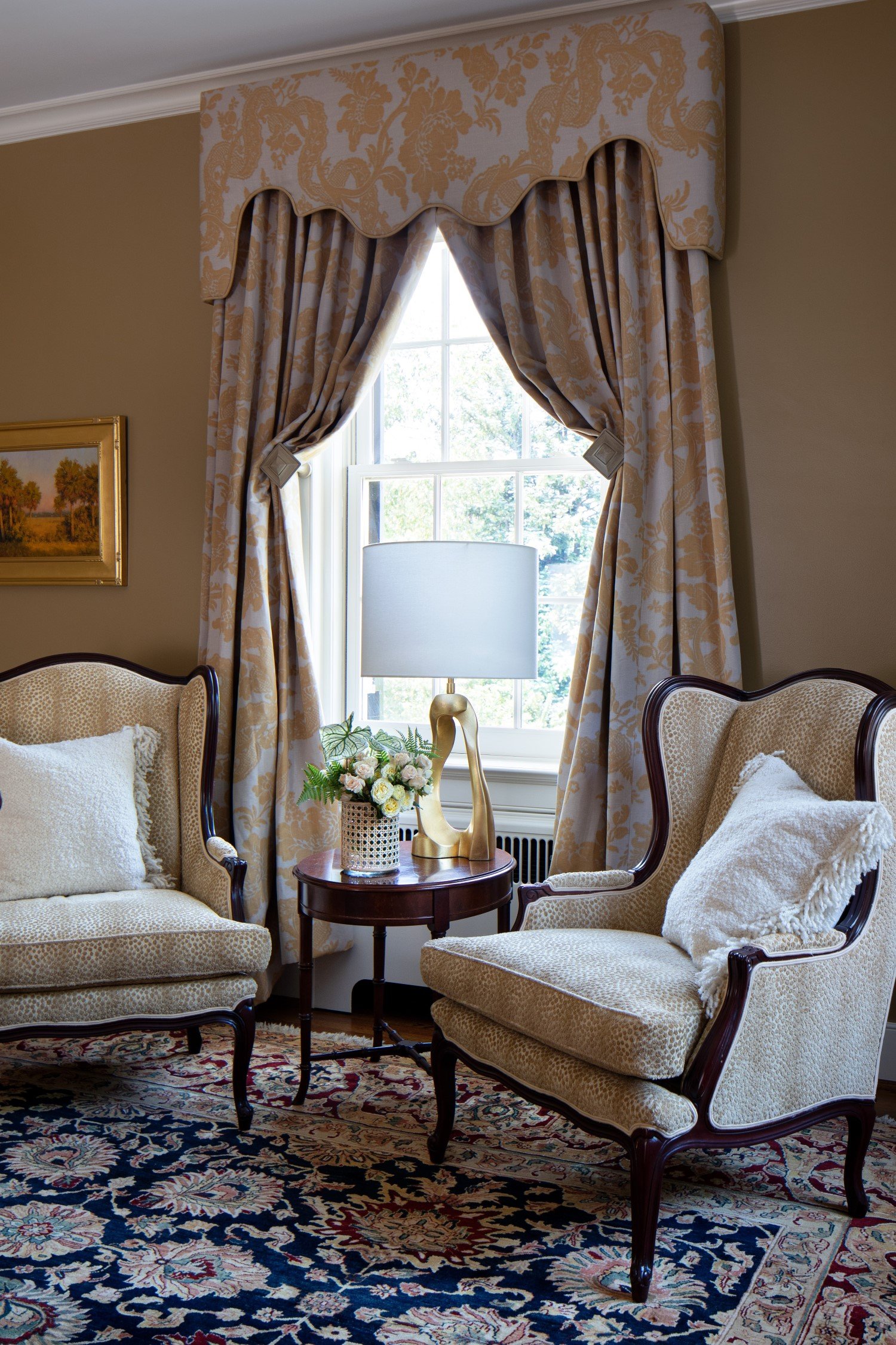  Traditional wing-back chairs, a Turkish rug, and a fluted valance covered in a floral damask that matches the drapes 