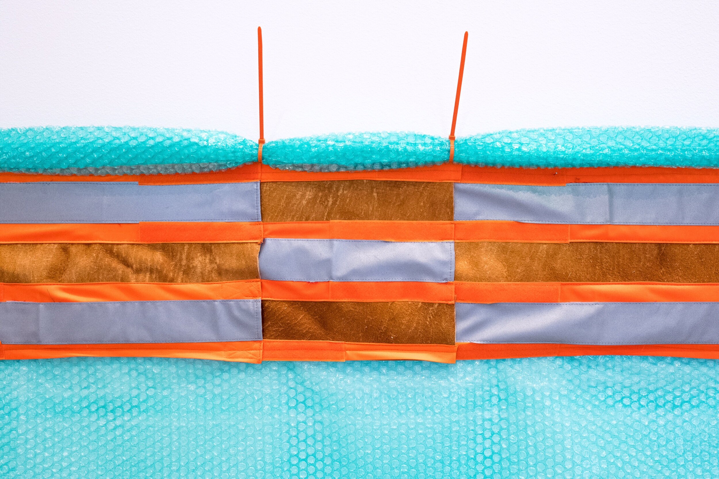  Detail of “Delta Trim” (2018) Bubble wrap, reflective tape, velcro, zip ties, moose hide; 261” x 19” 
