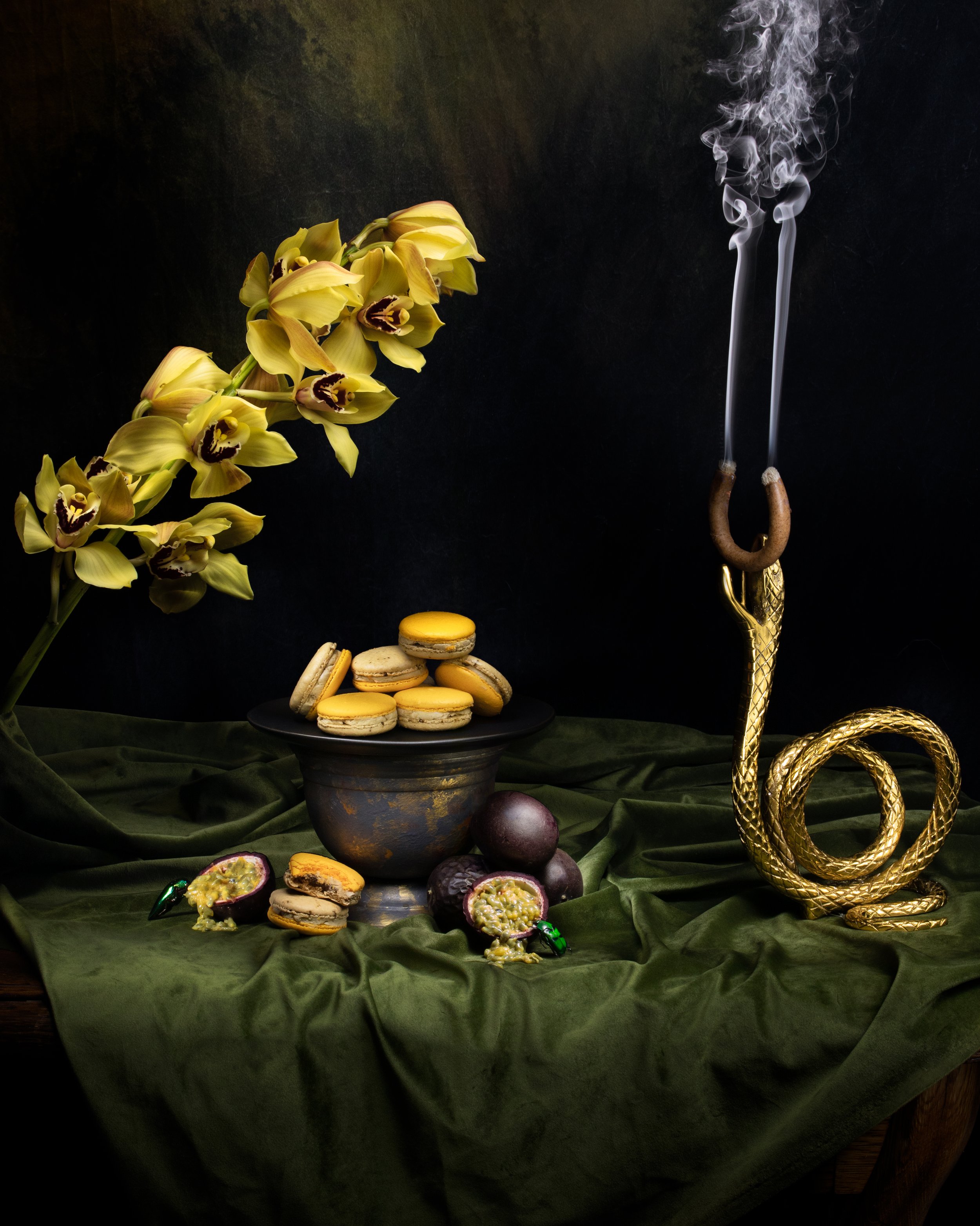 Smoky passionfruit macarons arranged in a dramatic dessert still life. Cookbook photography by Nightflare Creative.