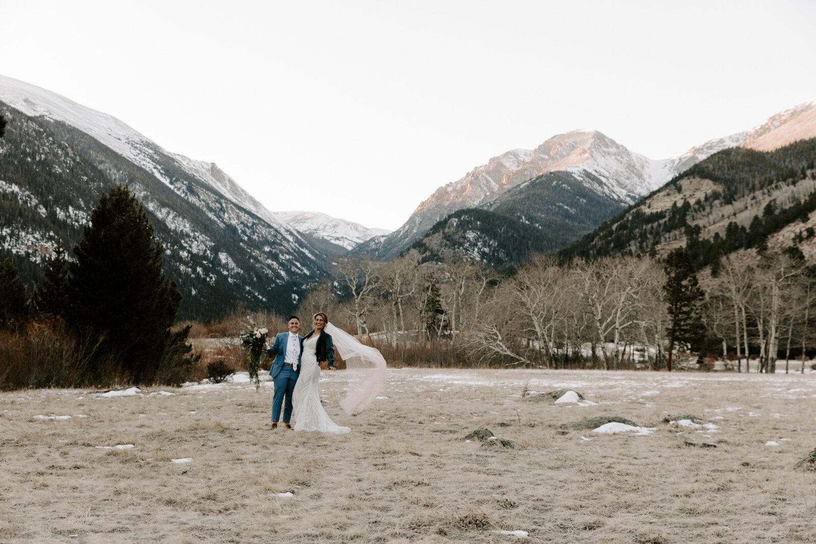 playful couple laughing and looking at the camera during winter elopement in Rocky Mountain National Park in Colorado at sunset with wedding photographer Diana Coulter