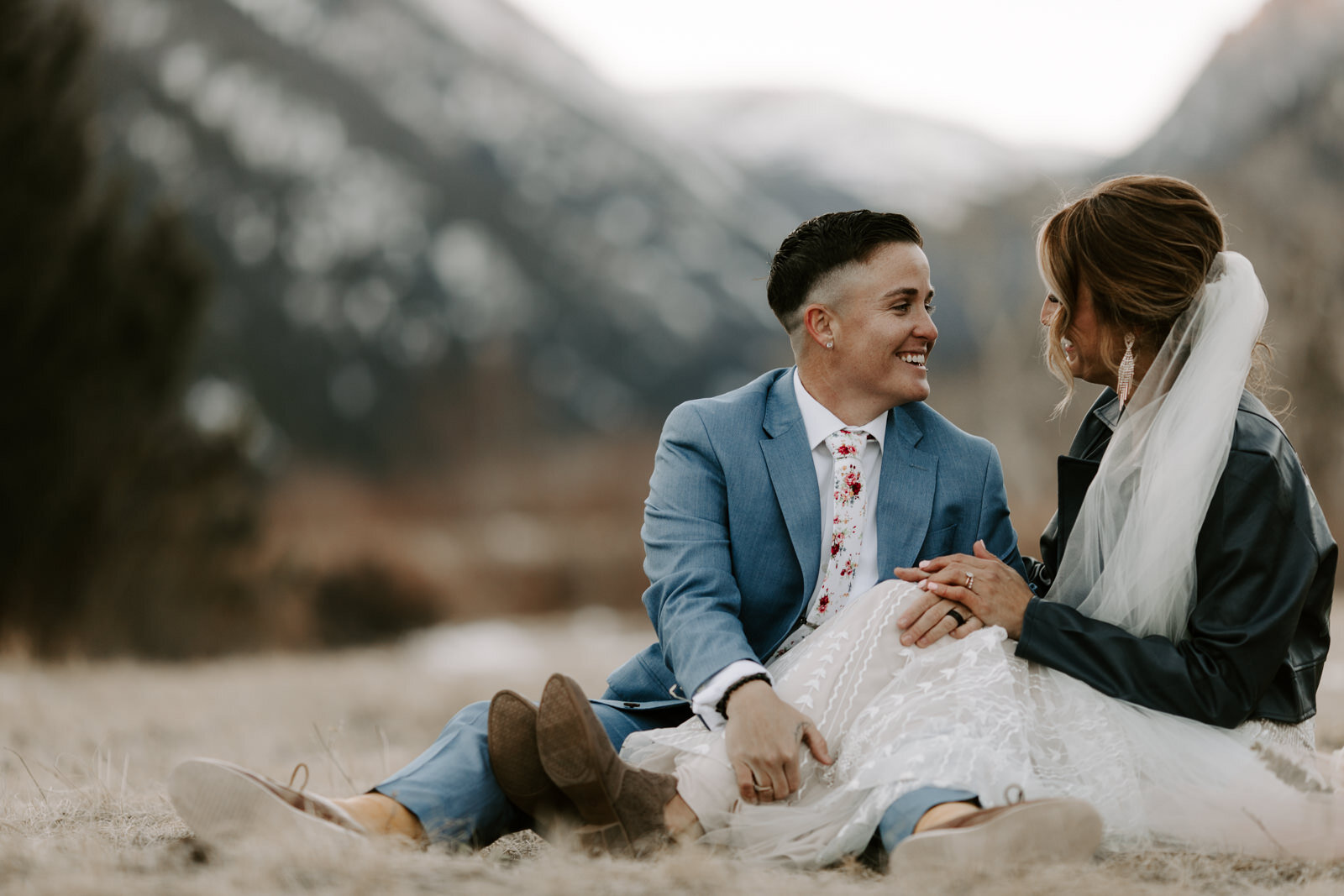 playful couple laughing and looking at each other while sitting in Rocky Mountain National Park during winter elopement in Colorado at sunset with wedding photographer Diana Coulter