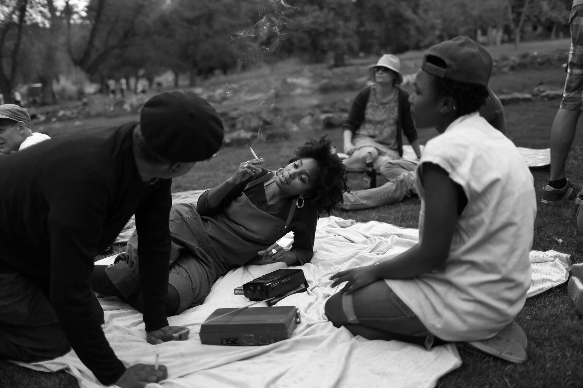 A black and white photograph of South African youth relaxing in a park during a radio event by South African photojournalist Alon Skuy, for Conde Contemporary.