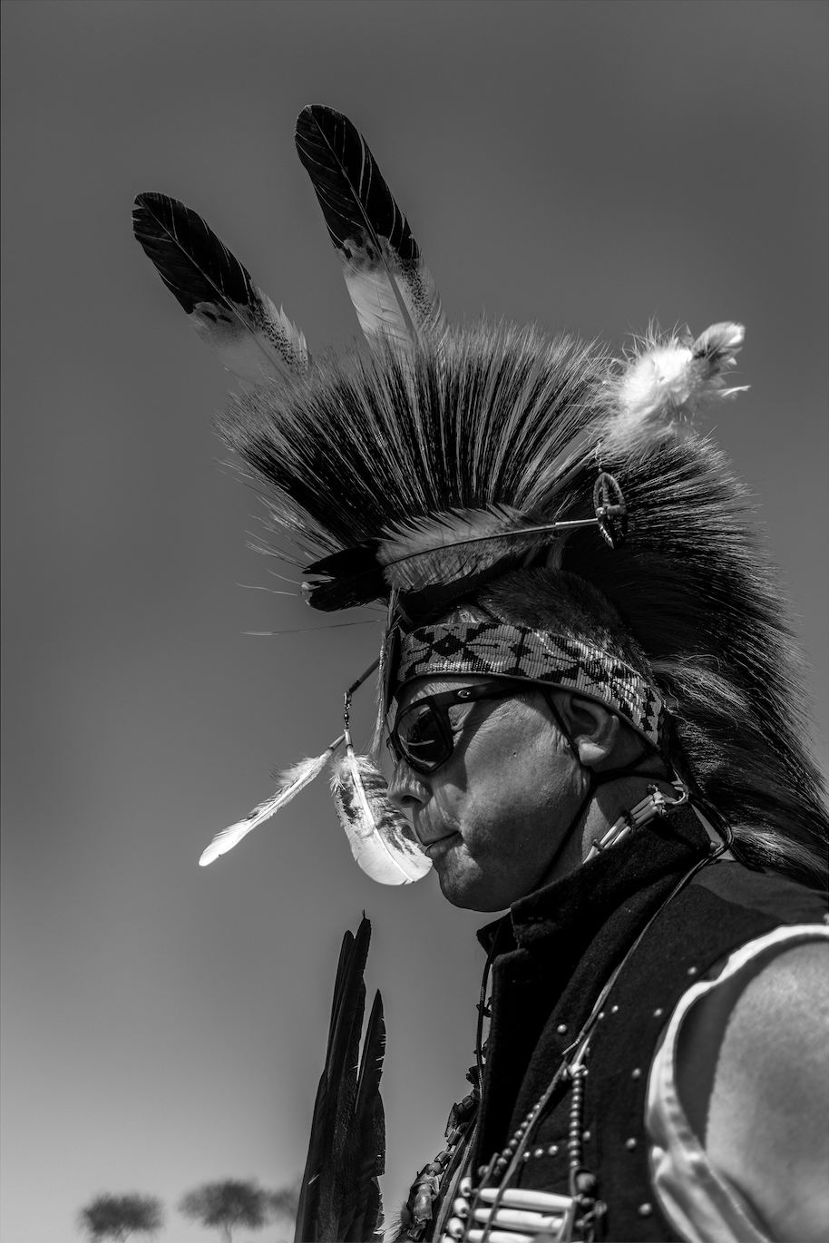 A black and white photograph of a Native American man at the Natchez Pow Wow in Natchez, Mississippi, photographed by contemporary fine art photographer Alon Skuy, for Conde Contemporary.