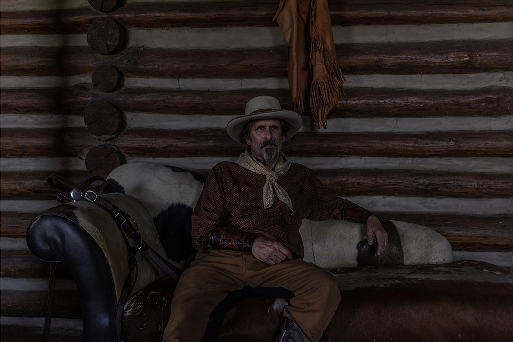 A color photo of a cowboy sitting in front of his house in Natchez, Mississippi, photographed by award winning photographer Alon Skuy, for Conde Contemporary.