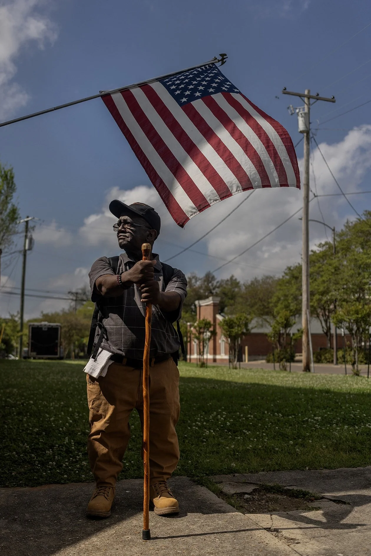 A photograph of Tommy, the unofficial mayor of Natchez with an American flag behind him, photographed by South African photographer Alon Skuy for Conde Contemporary.