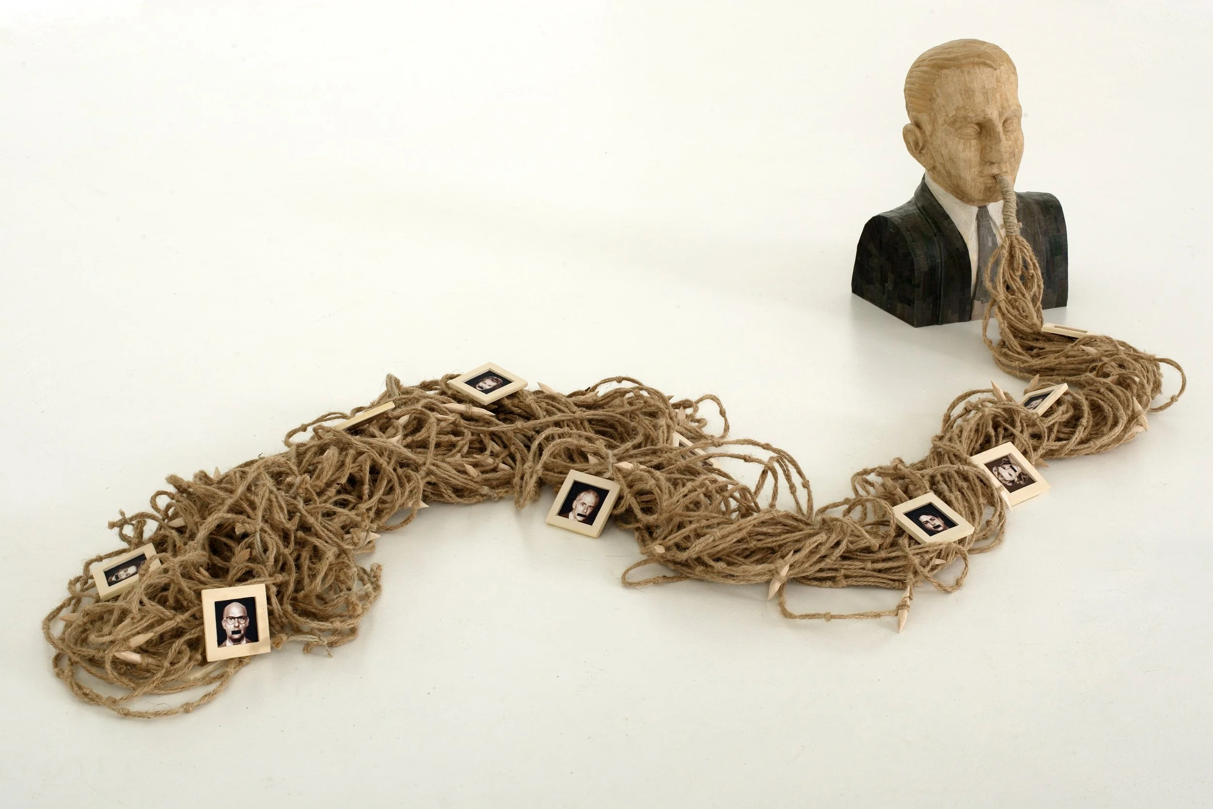 A sculpture by Cuban conceptual artist, Rubén Torres Llorca, titled Political Speech featuring the bust of a man with barbed twine coming out of his mouth and small square paintings of people with a black bar painted across their mouths.