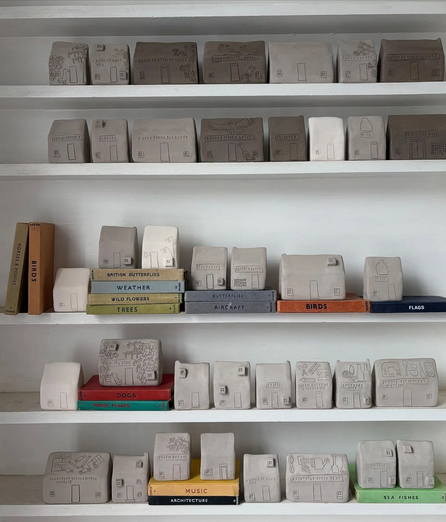 This is what my houses look like before they are fired and glazed and then Raku fired. They are all hand built like little flat packs and are hollow in the centre. 

The windows are all neatly cut out and I draw all the illustrations on by hand with 