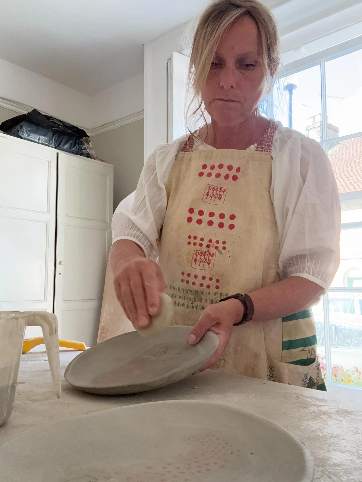 These plates are made in a press mold and when they are taken out they need trimming and wiping around the edge with a sponge. It is one of my favourite jobs as the plates come to life and become their true shape. 

As they are all handmade it is som