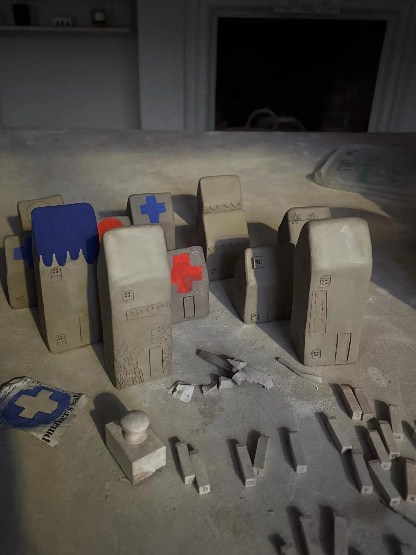 My work table now at the end of a day house building. 
Today I have returned to an old favourite method of using stencils and stains to make some crosses, circles and scallops onto the roofs. 

I am making houses until the end of this week so if you 