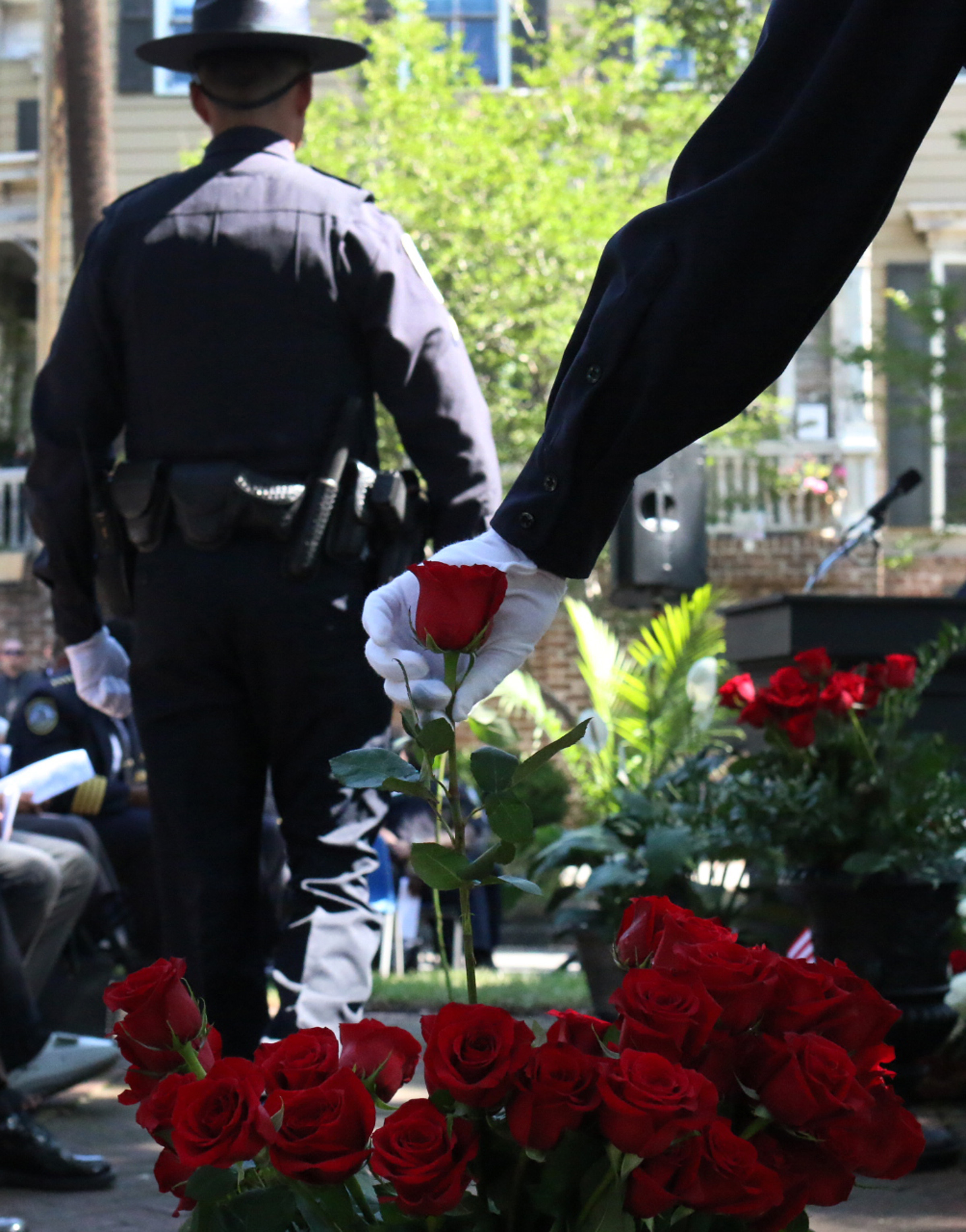  A police officer grabs a rose to add to the Fallen Officer Memorial in front of Savannah-Chatham police headquarters May 11, 2016, during a ceremony honoring law enforcement officers who died in the line of duty. &nbsp;(Dash Coleman/Savannah Morning