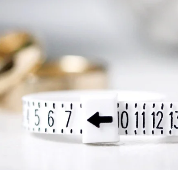 Close-up of a white measuring tape with an arrow pointing to the number 6, placed on a white surface.
