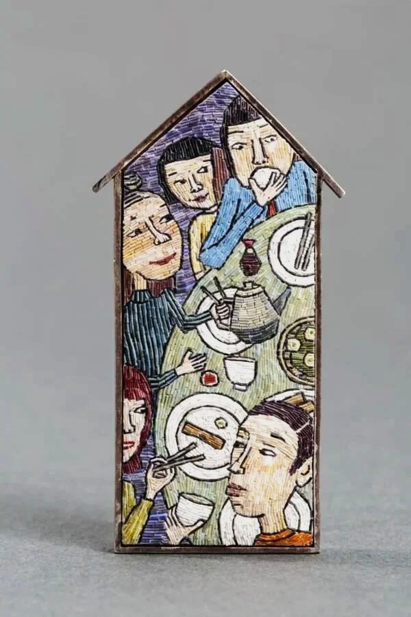 Colorful illustration of people sitting around a dining table, eating and drinking, with a house-shaped border.