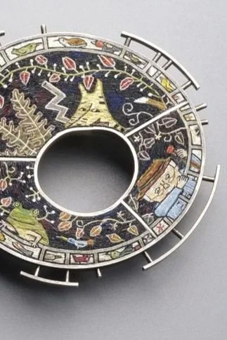 Decorative circular metallic object with Christmas-themed illustrations, including a Christmas tree, presents, and winter scenery, designed to resemble a clock face without hands.