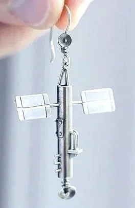 Close-up of a metallic miniature airplane model with solar panel-like wings, set on a white surface.