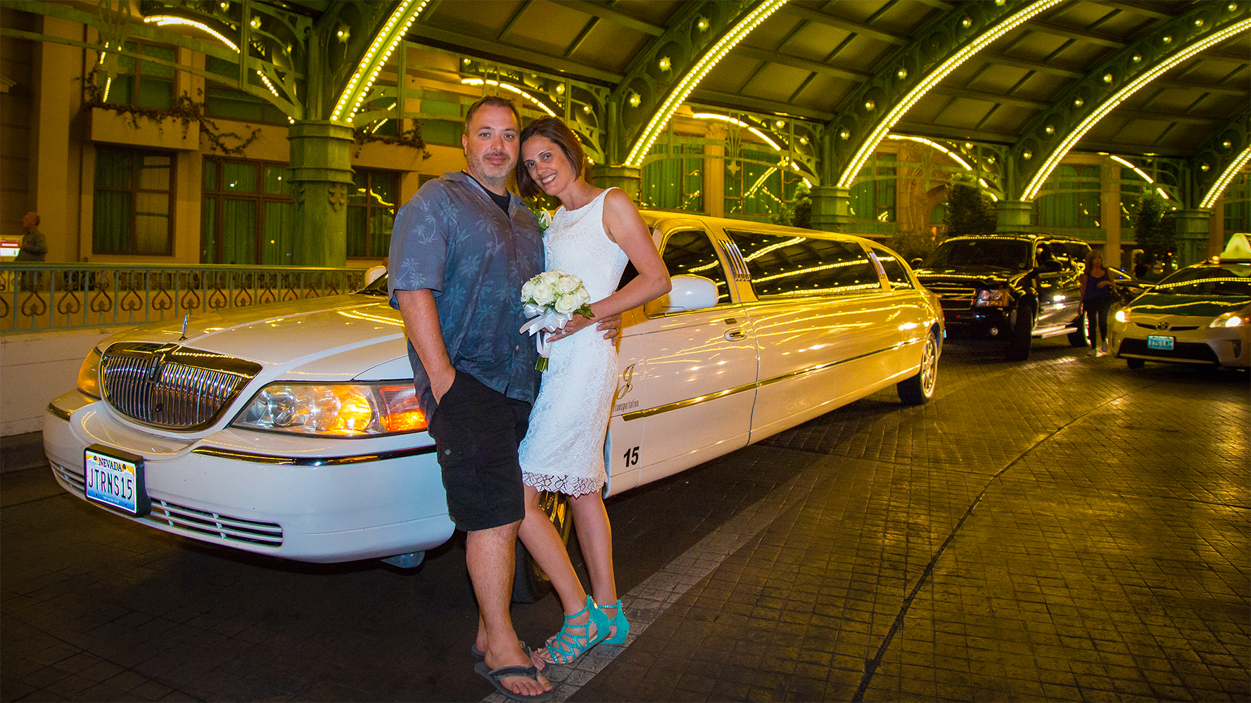 Couple posing in front of limousine in Las Vegas at night