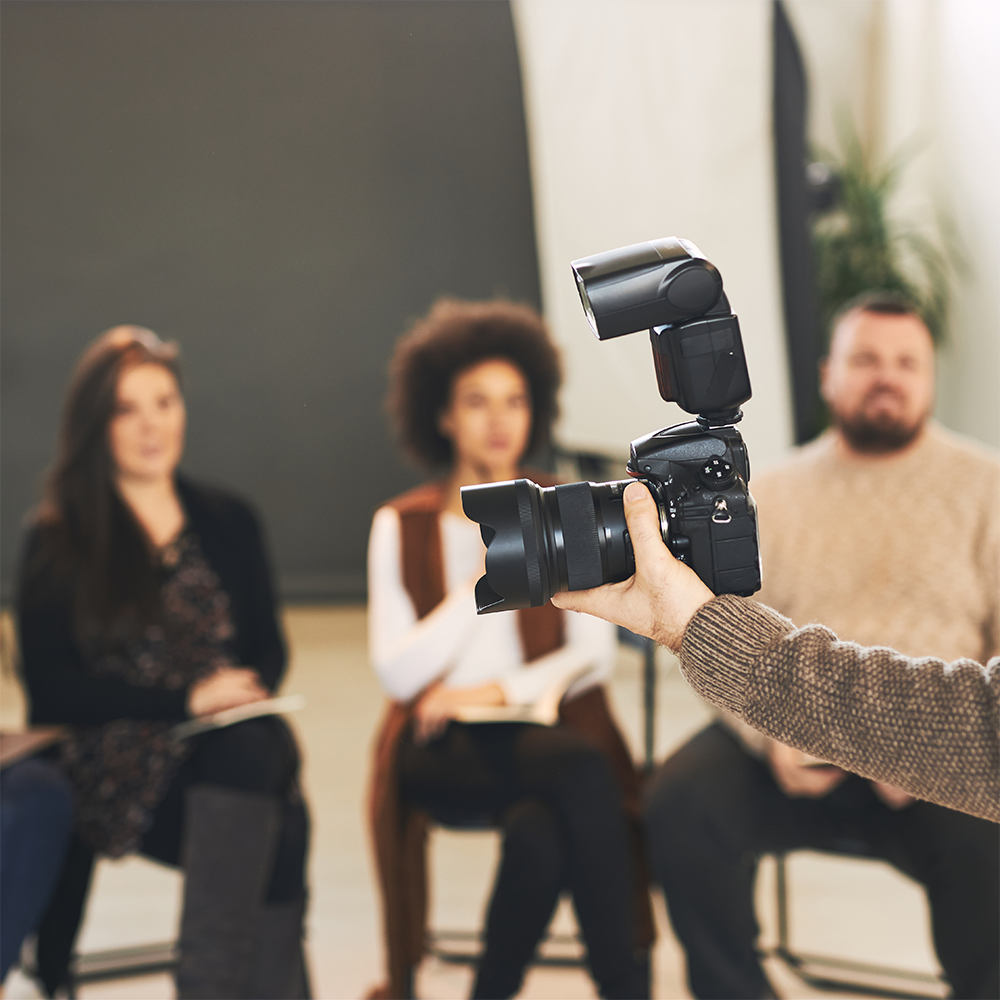 Photography class demonstrating camera flash techniques with students seated in a workshop setting.