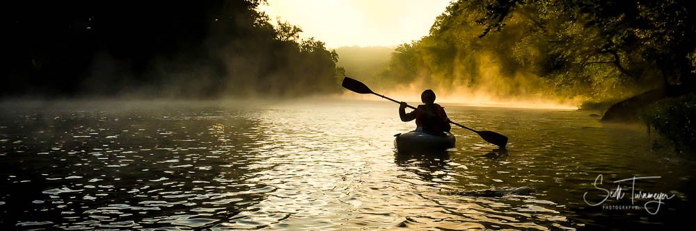 Golden hour kayaking scene with soft morning light and mist over calm water